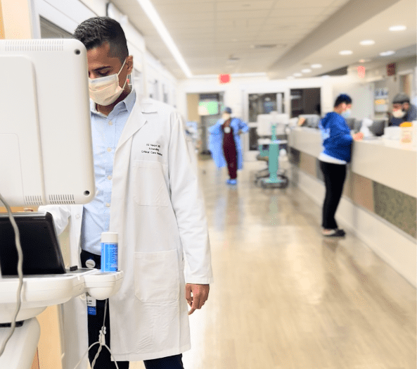 Critical Care Fellow looking at a computer in a hospital hallway